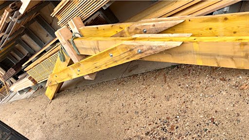Fermes de charpente en bois assemblées par des moises boulonnées, stockées à l’atelier
