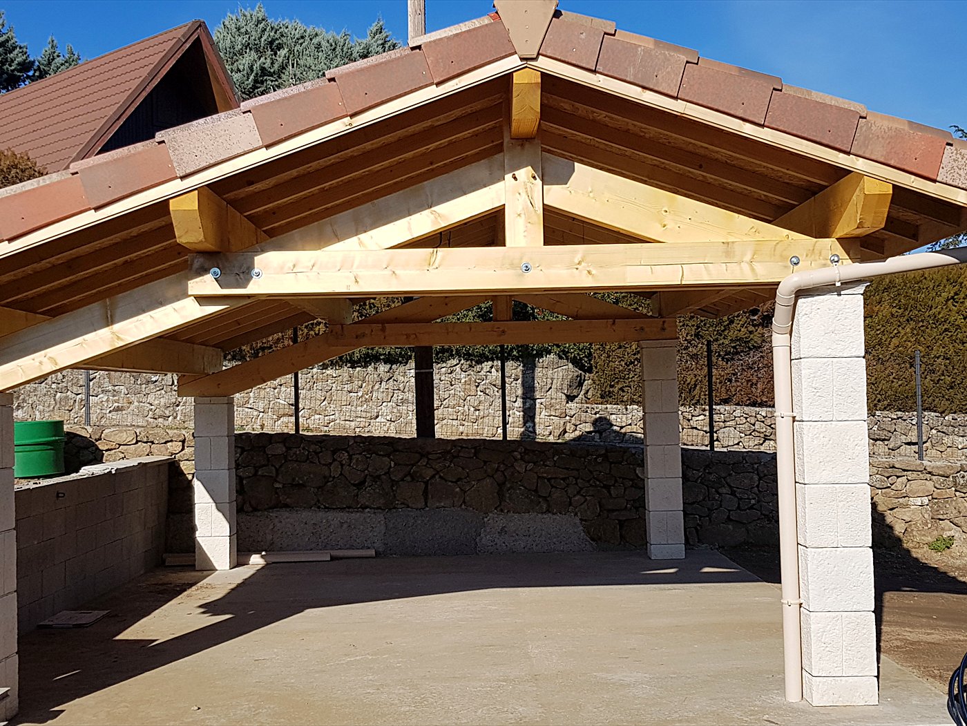 Préau en charpente bois : ferme apparente en pignon, pannes et chevrons sous couverture tuiles